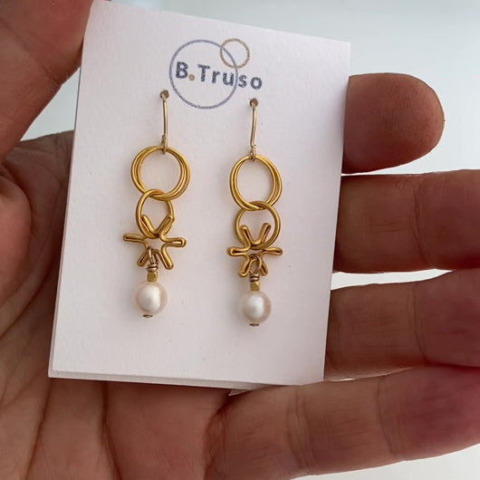 Earrings made with dangling elements of 24kt gold plate over sterling silver circles and freshwater pearls